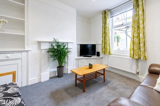 Bright furnished living room with a sofa, television, coffee table, fireplace and large window.