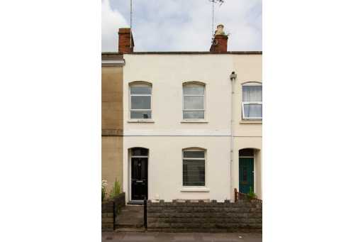 Front exterior of a row of attached houses with doors, windows, brick chimneys and low front walls.