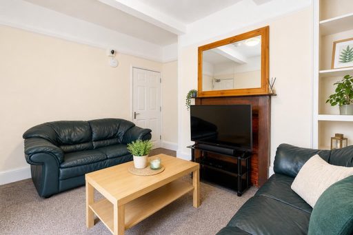Living room with leather sofas, a coffee table, television and fireplace.
