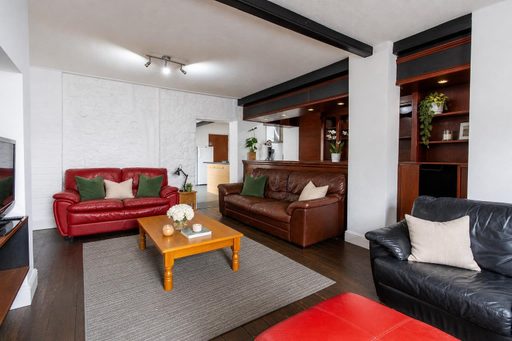 Living room with red, brown and black leather sofas, a wooden coffee table and a grey rug.
