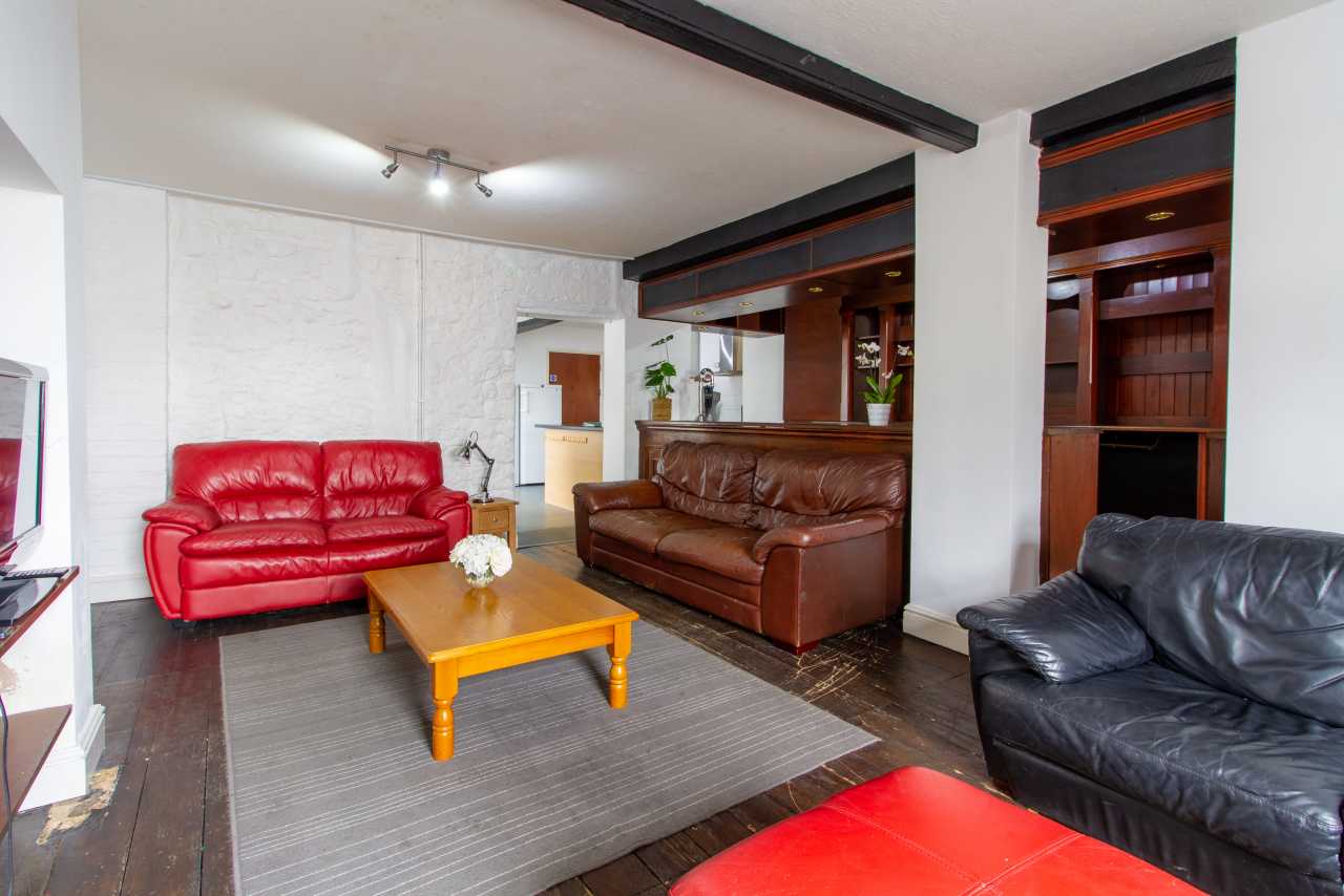 Living room with red, brown and black leather sofas, a wooden coffee table and a grey rug.