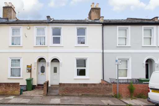 Street view of adjoining two-storey terraced houses with painted facades, front doors, windows, chimneys and small front areas.