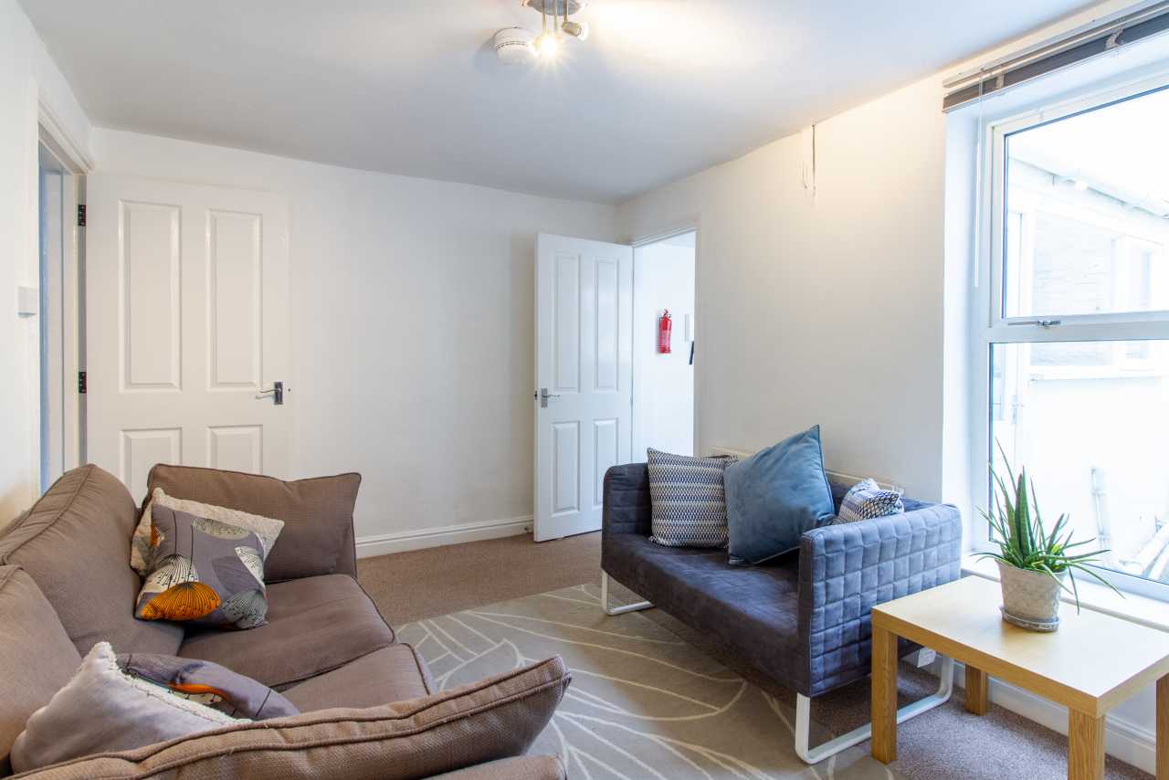Bright furnished living room with two sofas, a rug, a coffee table and a large window.