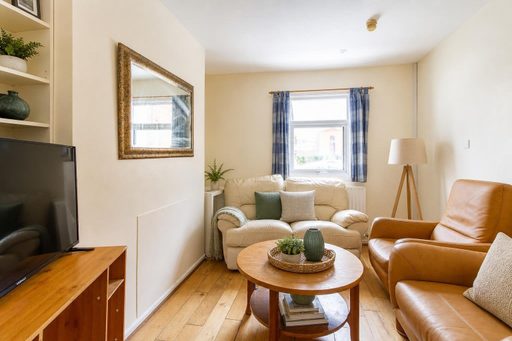 Living room with sofas, armchair, television, coffee table, wooden floor and a window.