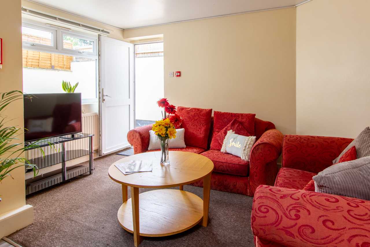 Furnished living room with red sofas, a coffee table, television and open patio door.