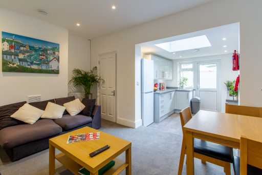 Open-plan living and dining area with a sofa, coffee table, dining table, and adjoining kitchen.