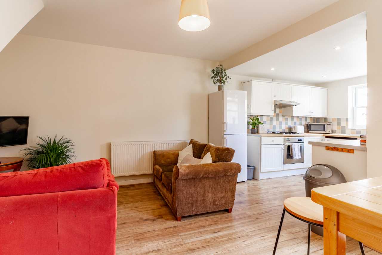 Open-plan living area with sofas, dining table and a fitted kitchen.