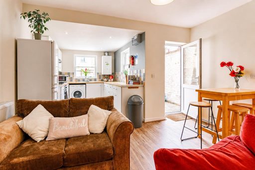 Open-plan living and dining area with a sofa, dining table, and visible kitchen.