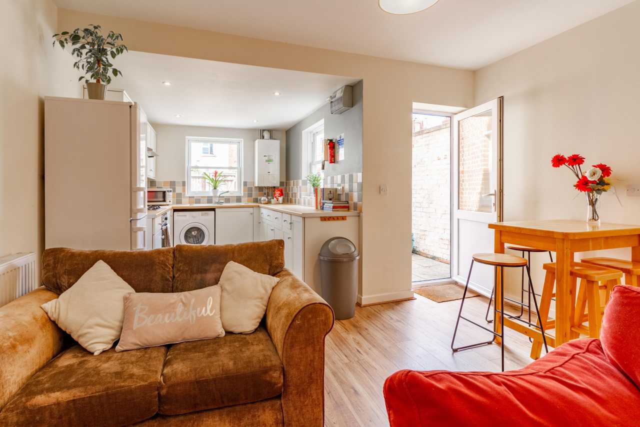 Open-plan living and dining area with a sofa, dining table, and visible kitchen.