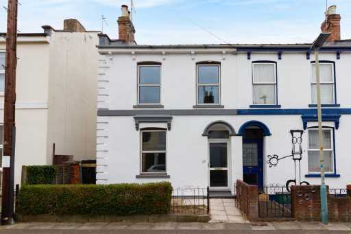 Street view of adjoining white-painted terraced houses with upper-floor windows, front doors, small fenced gardens and pavement.
