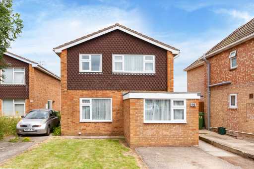 Front exterior of a brick two-storey house with a small lawn, driveway and parked car.