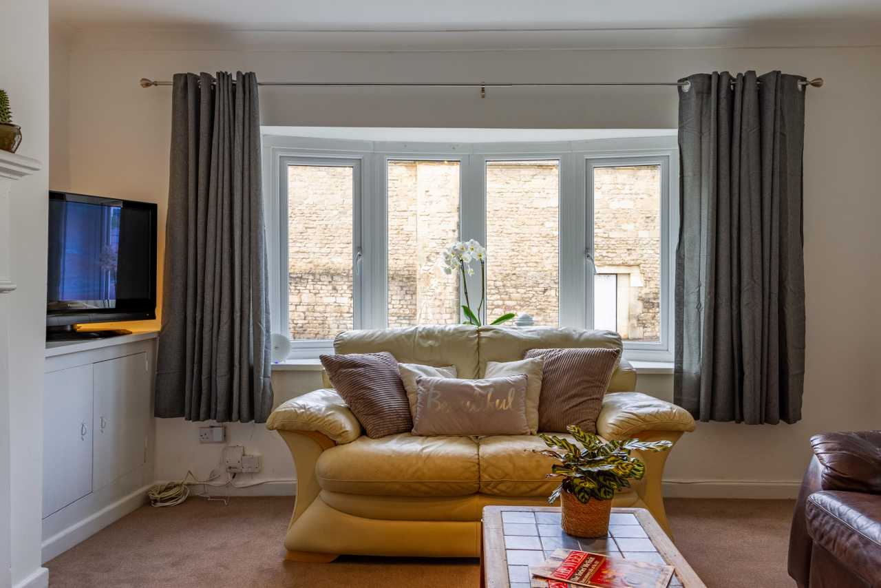 Living room with a sofa, television, curtains, bay window and coffee table.