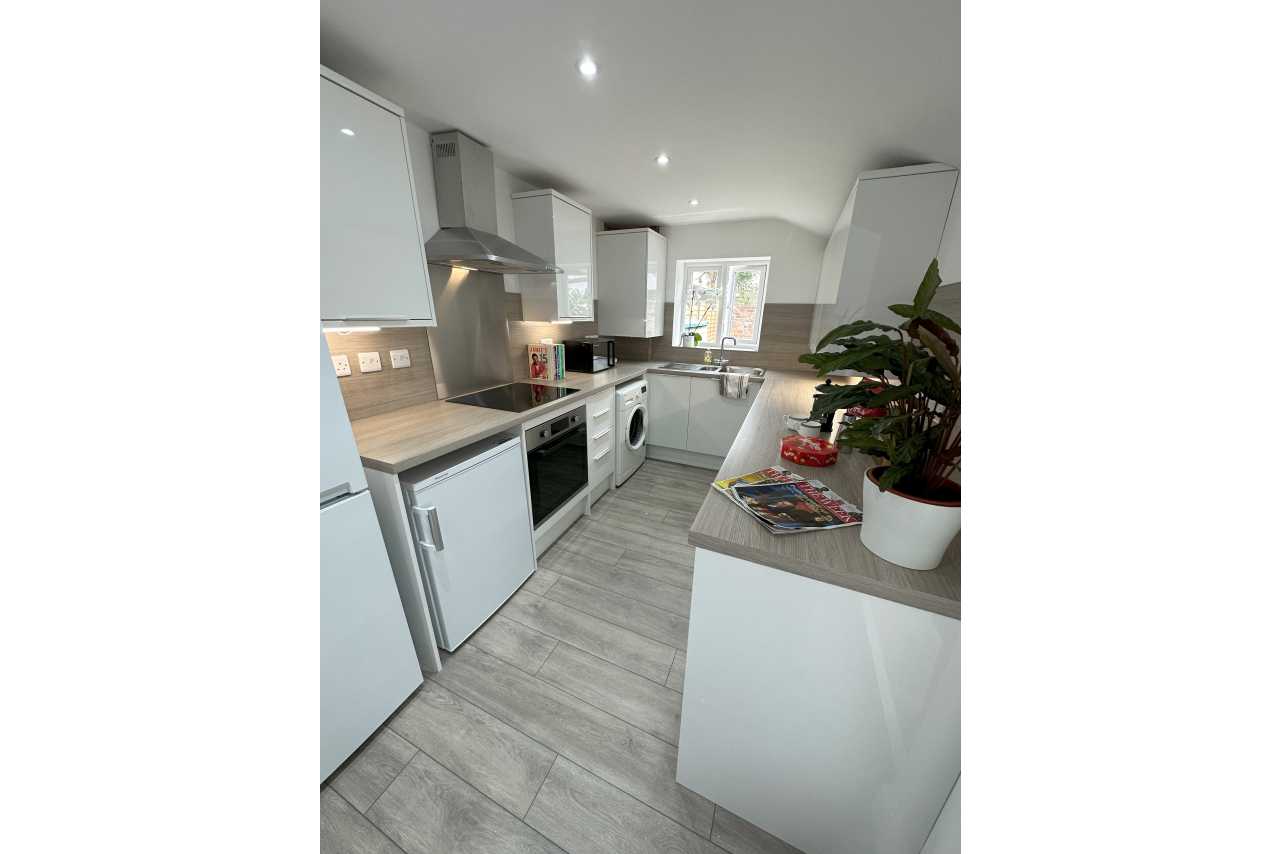 Bright modern kitchen with white cabinets, appliances, a central island and dining area.