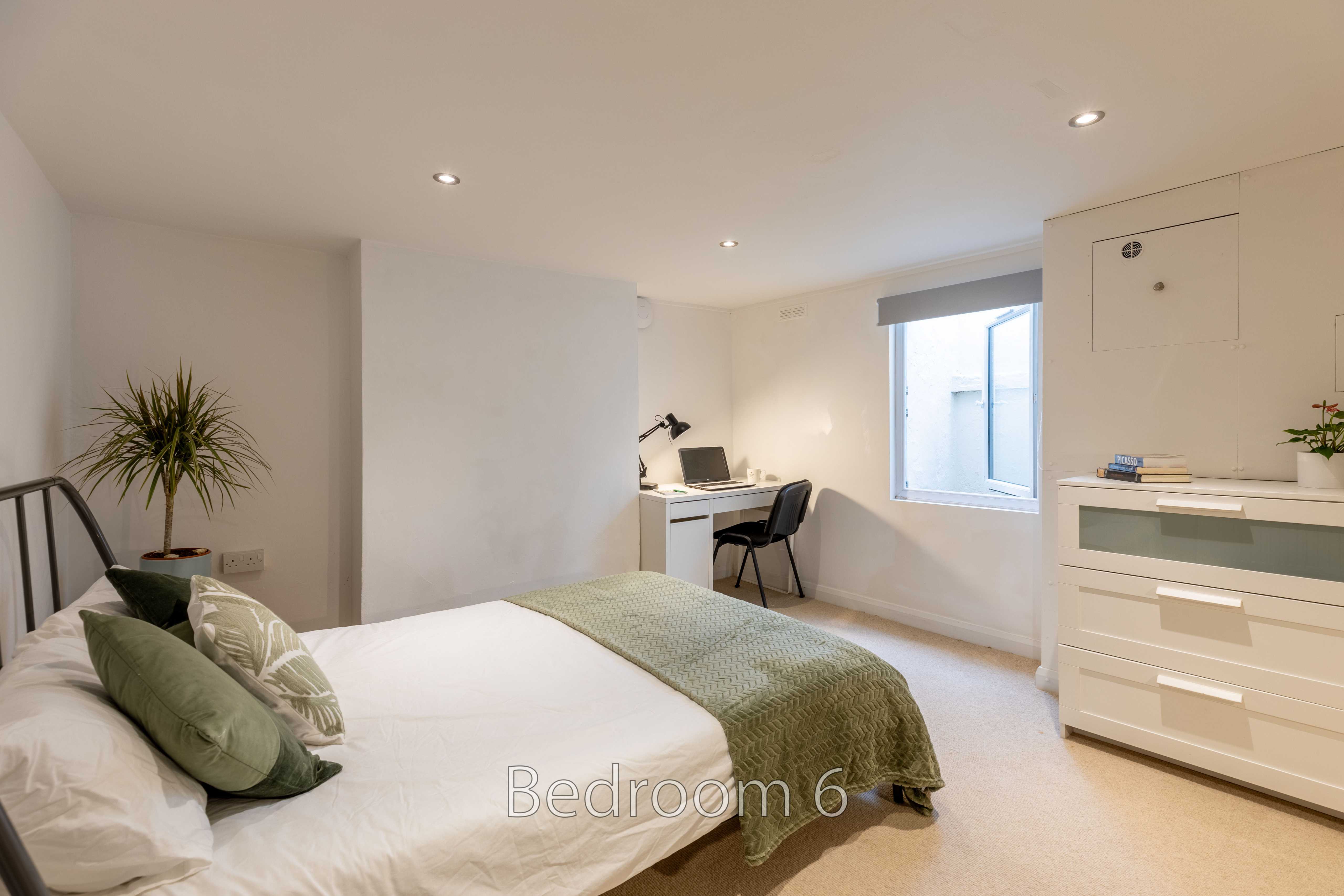 Bedroom with a bed, desk, chair, chest of drawers and window.