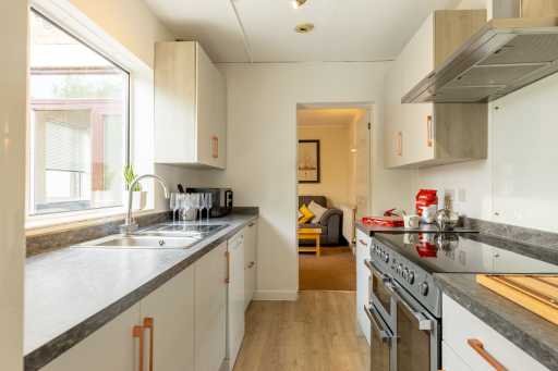 Bright fitted kitchen with cabinets, sink, countertops, and a large range cooker.