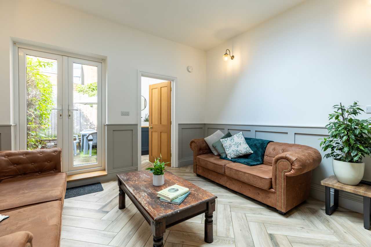 Furnished living room with sofas, a coffee table, a glass door, and a potted plant.