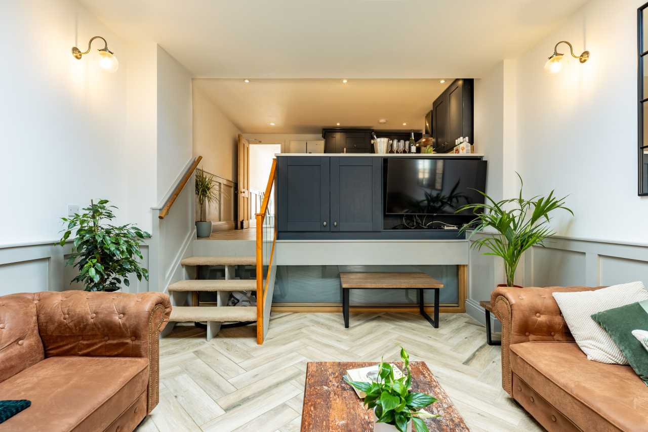 Living room with sofas, a television, stairs and an open kitchen.