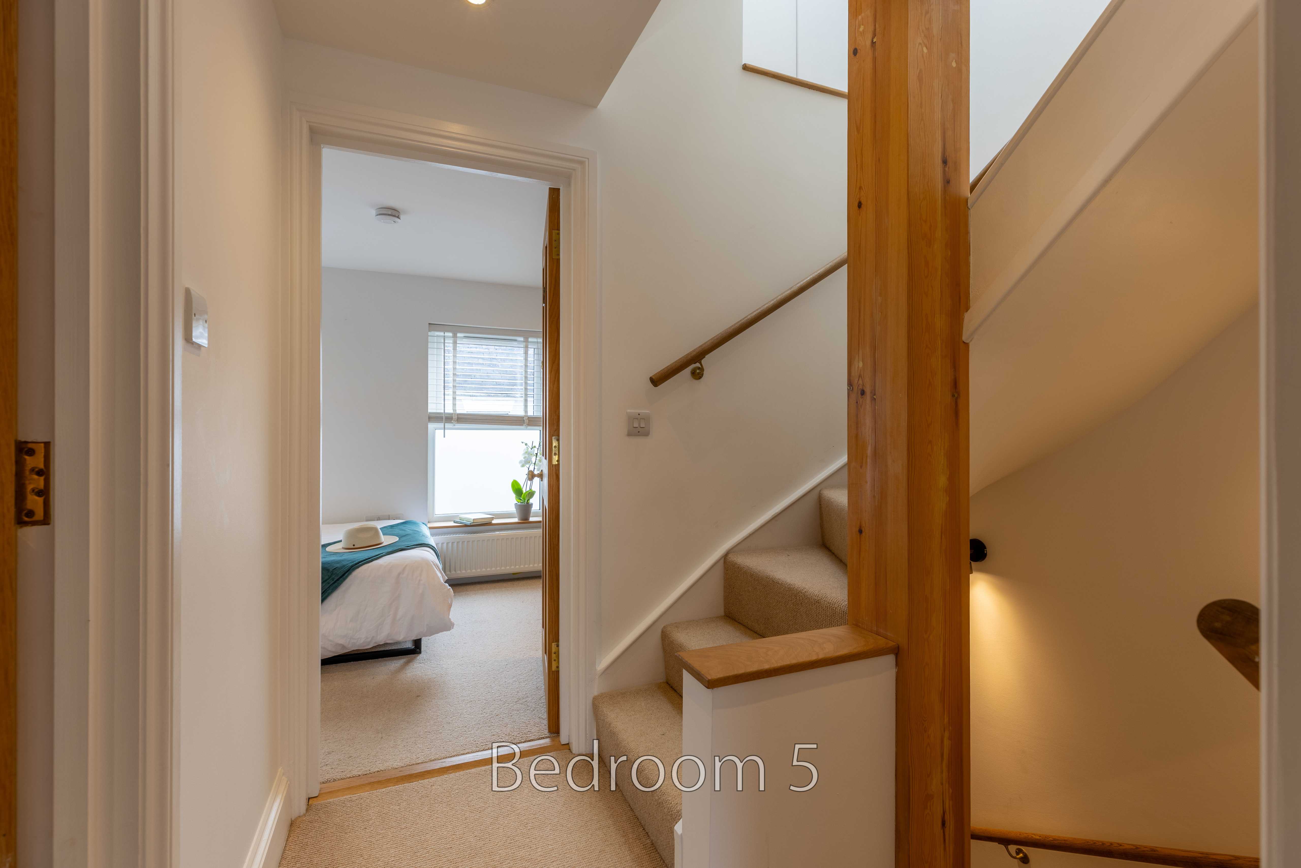 A bedroom visible through a doorway beside a carpeted staircase.