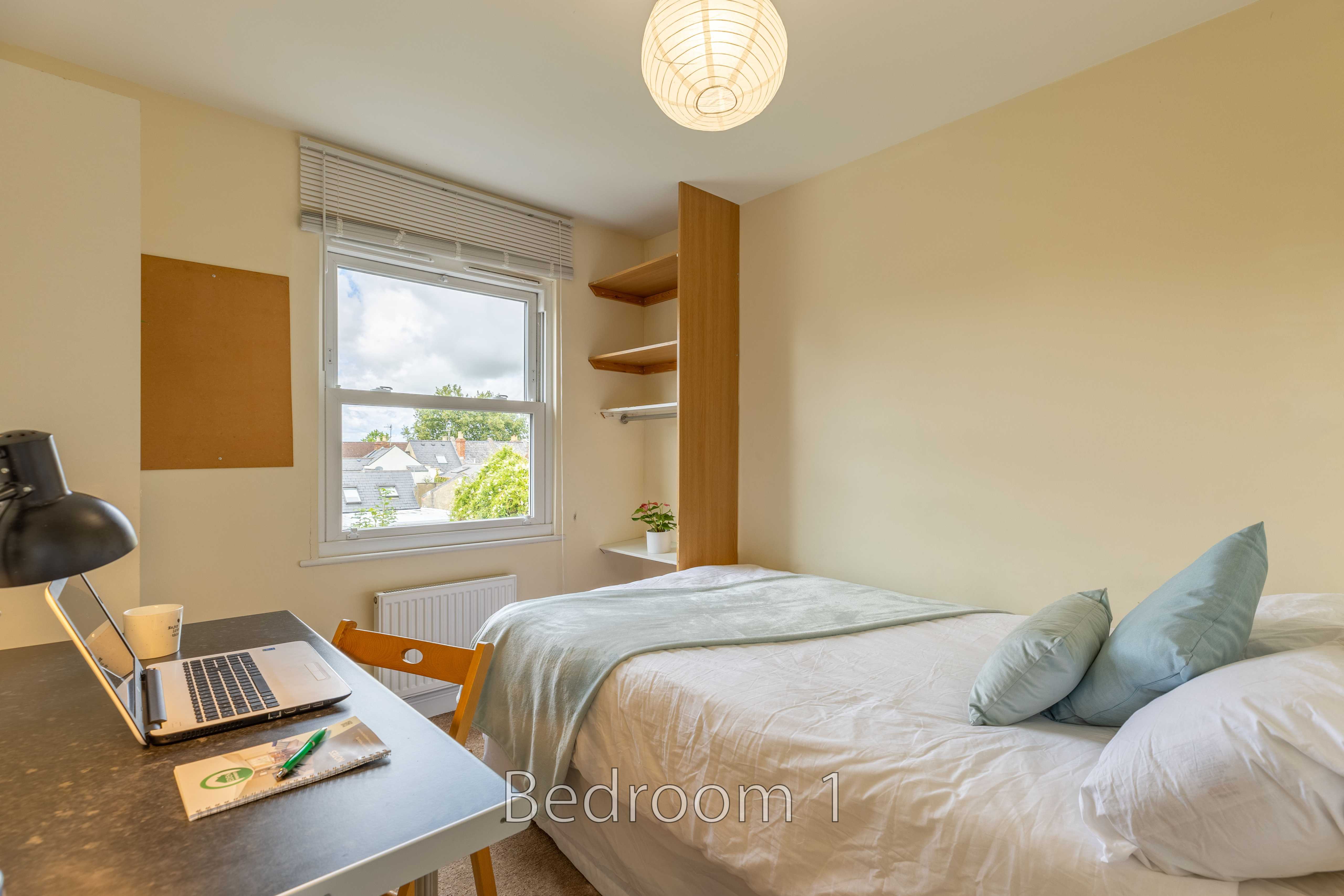 Bedroom with a double bed, desk, chair, window and built-in shelving.