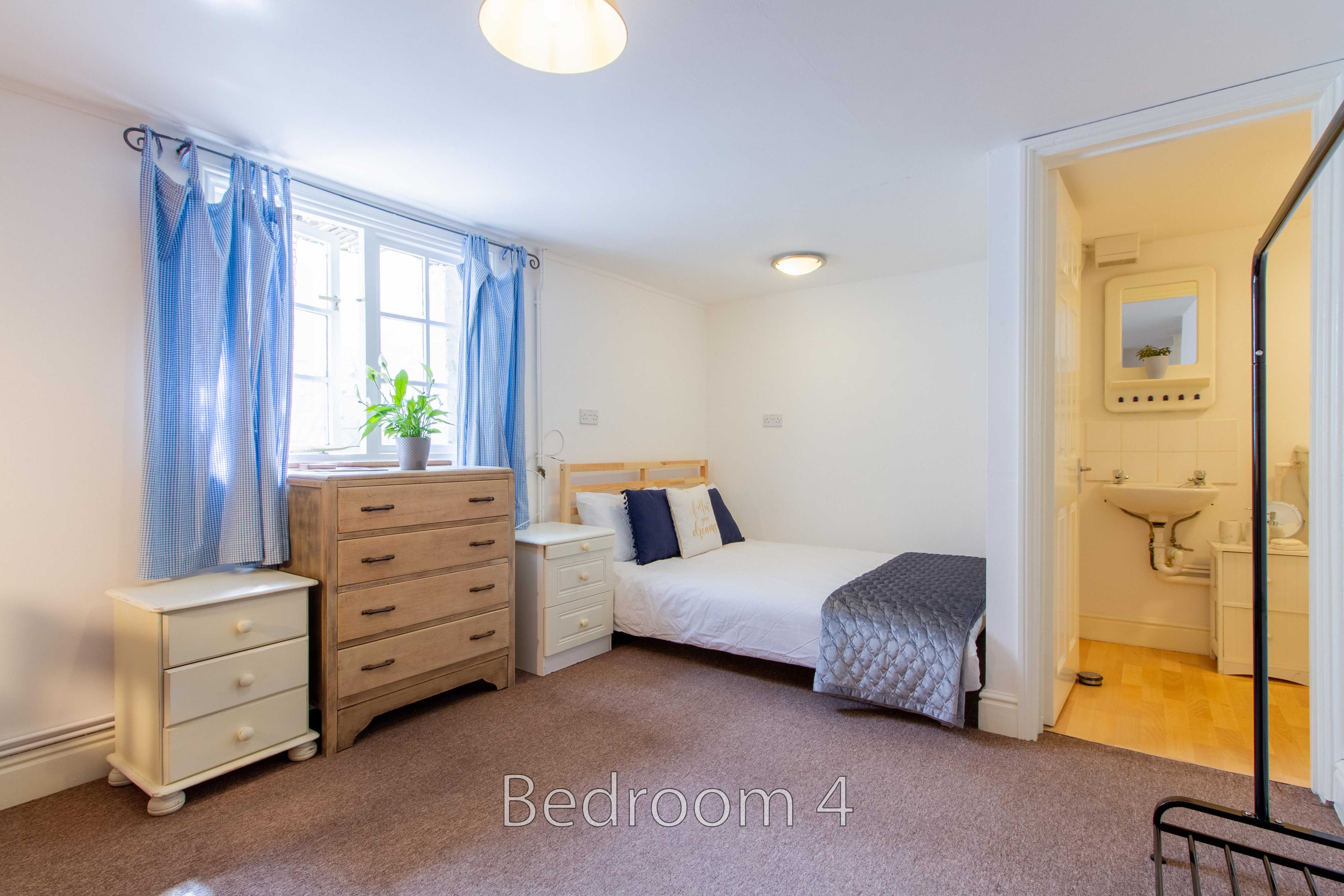A furnished bedroom with a double bed, chest of drawers, bedside tables, window and an adjoining bathroom.