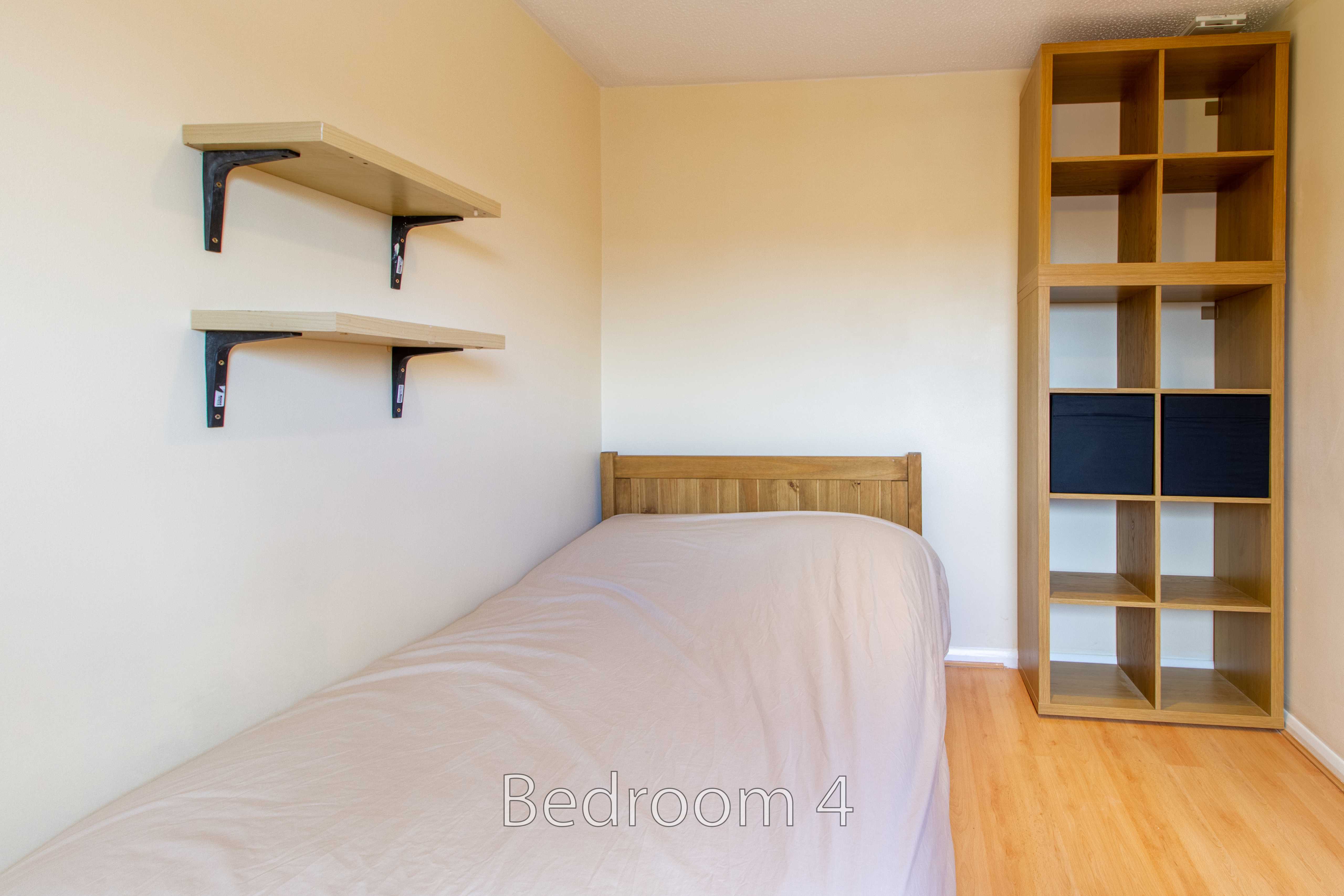 A single bed, wall-mounted shelves, and a tall wooden shelving unit in a bedroom.