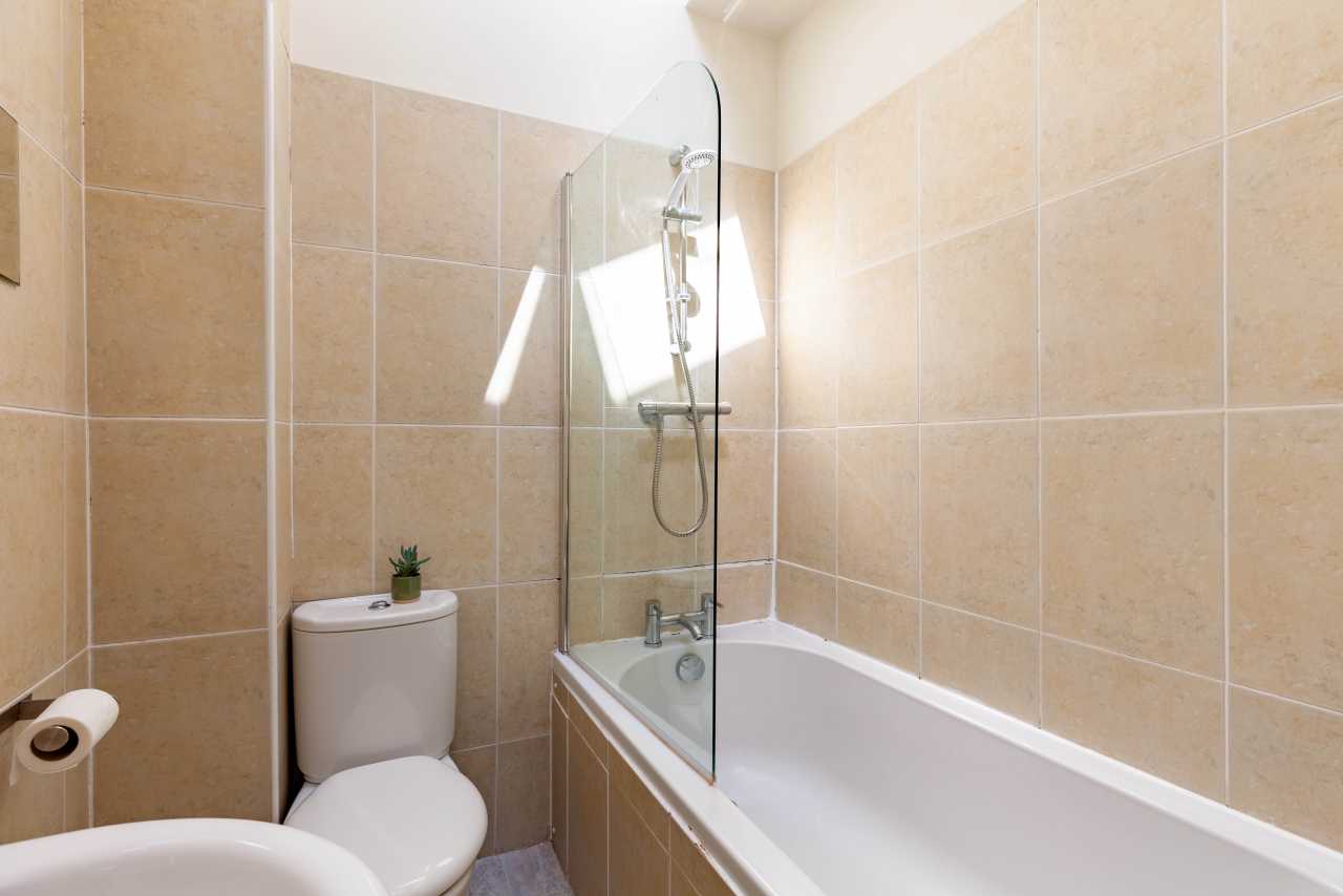 A tiled bathroom with a bathtub, shower, toilet and sink.