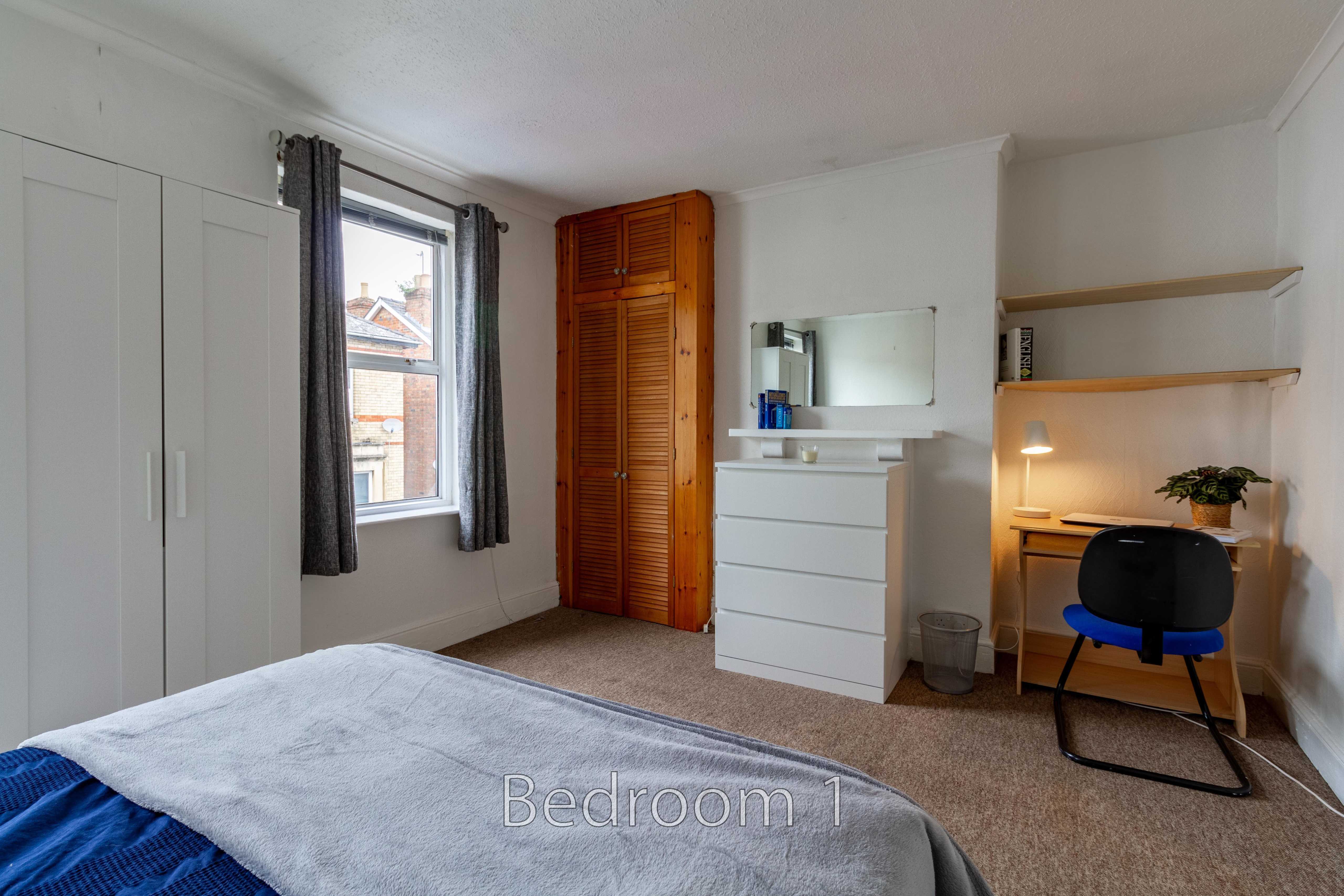 Furnished bedroom with a bed, wardrobe, window, dresser, mirror and desk.
