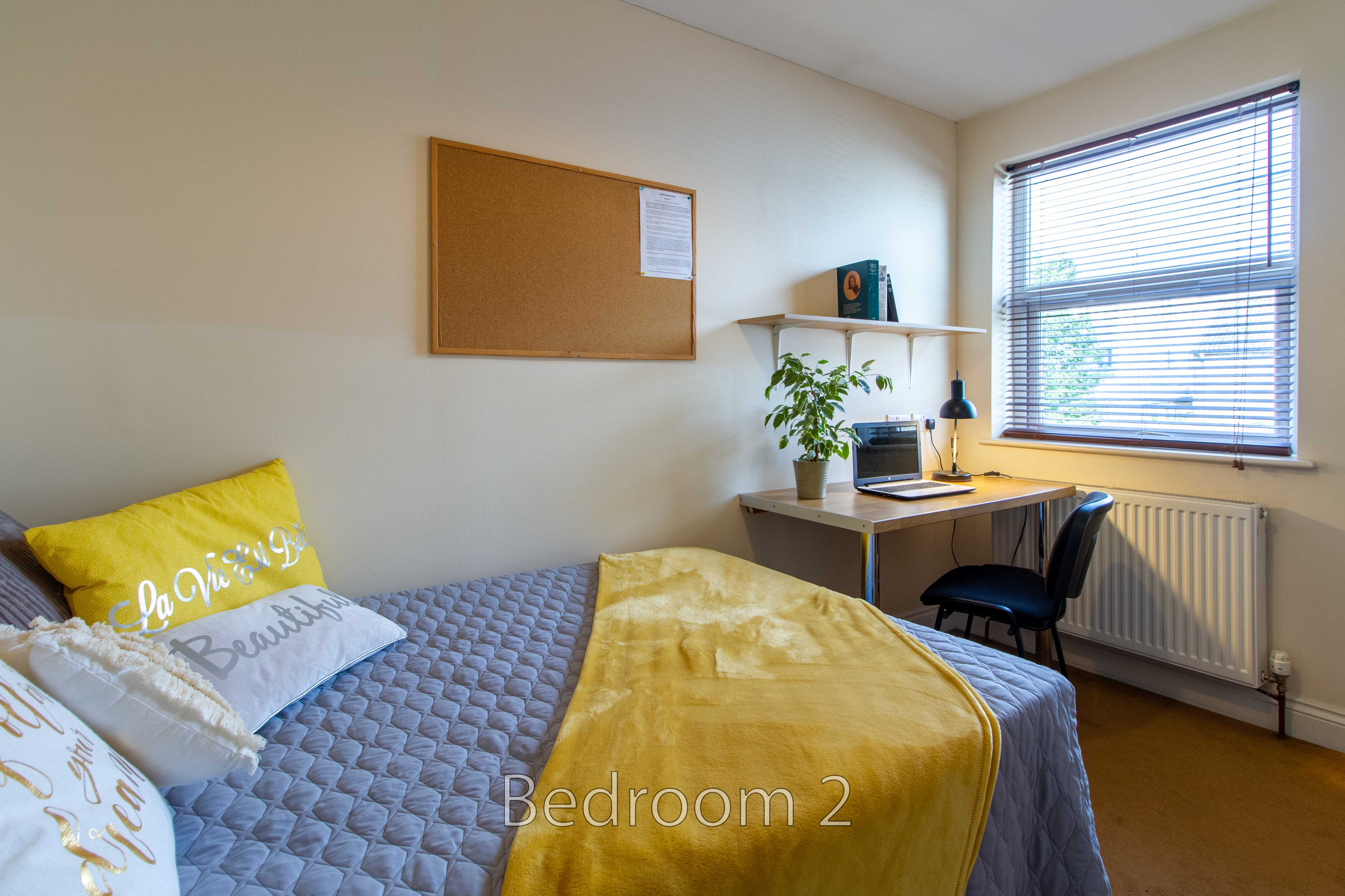 A furnished bedroom with a single bed, desk, chair, window, radiator and corkboard. The image is labelled “Bedroom 2”.