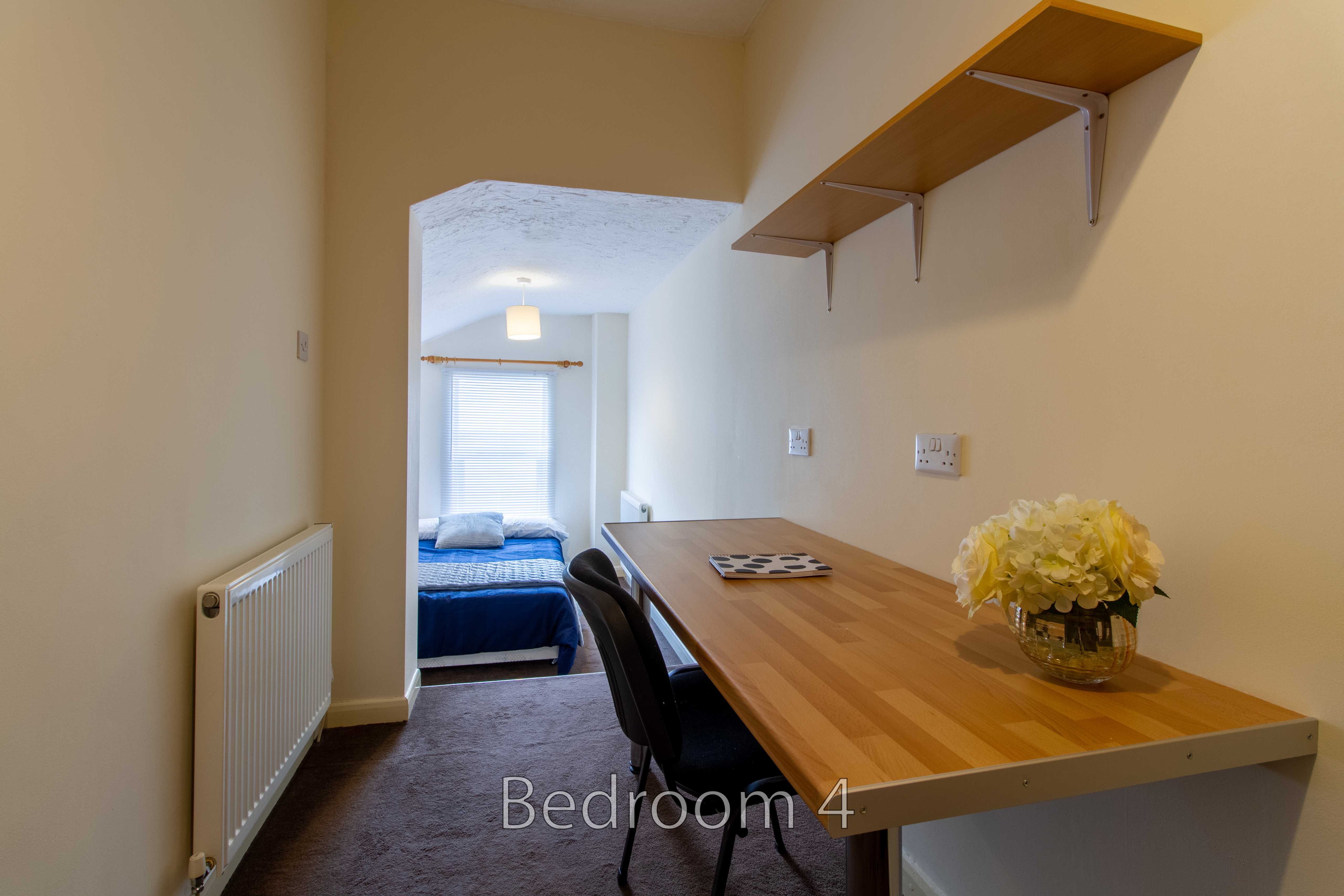 Bedroom with a single bed, desk, chair, wall shelves, radiator and window.