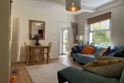 Bright living room with sofas, a dining table, a rug, windows and a glass door.