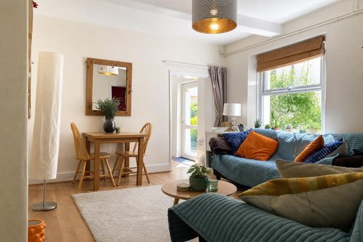Bright living room with sofas, a dining table, a rug, windows and a glass door.