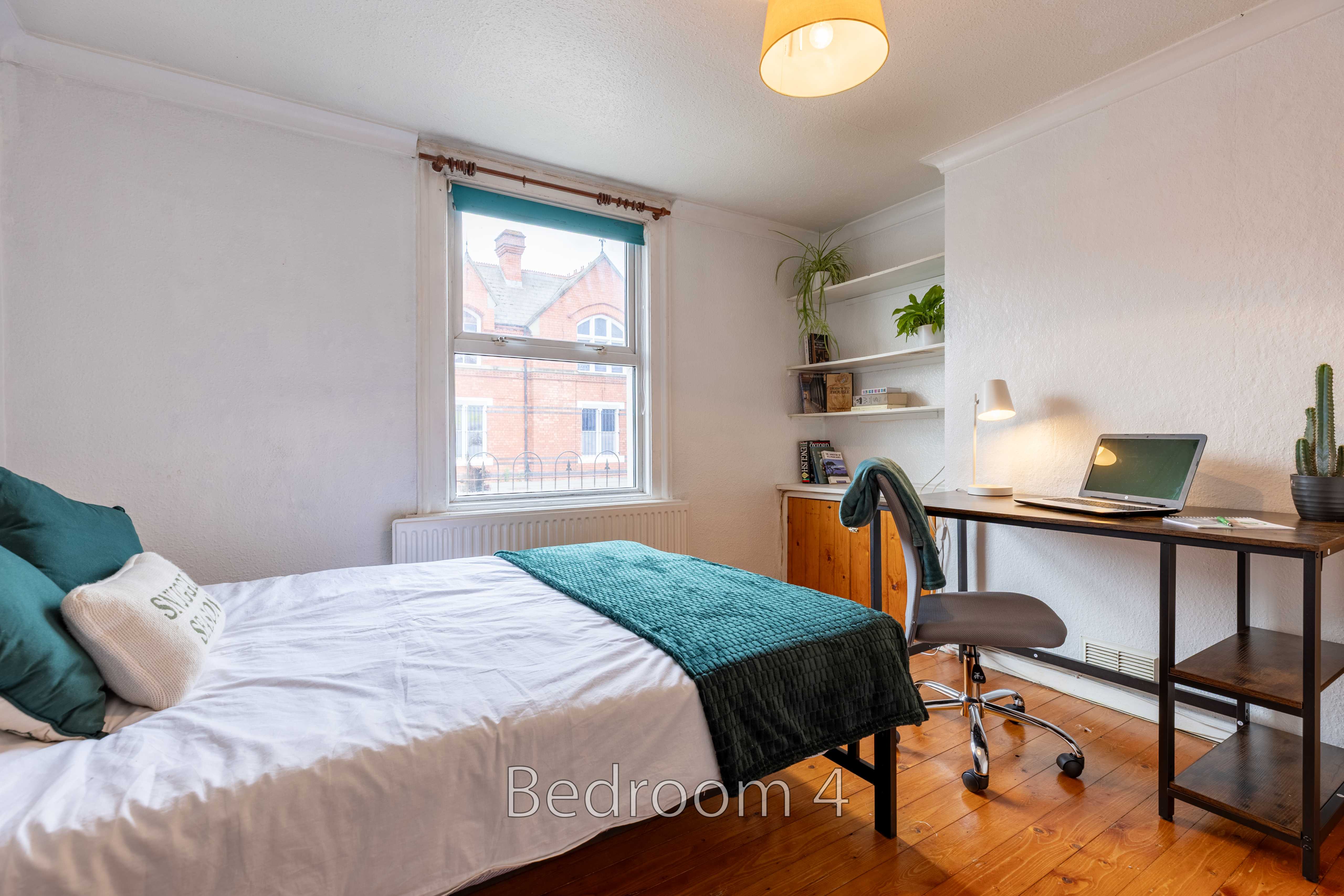 A bedroom with a bed, desk, chair, shelves, window and wooden floor.