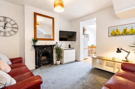 A furnished living room with red sofas, a decorative fireplace, television, cabinet, coffee table and doorway to a dining area.