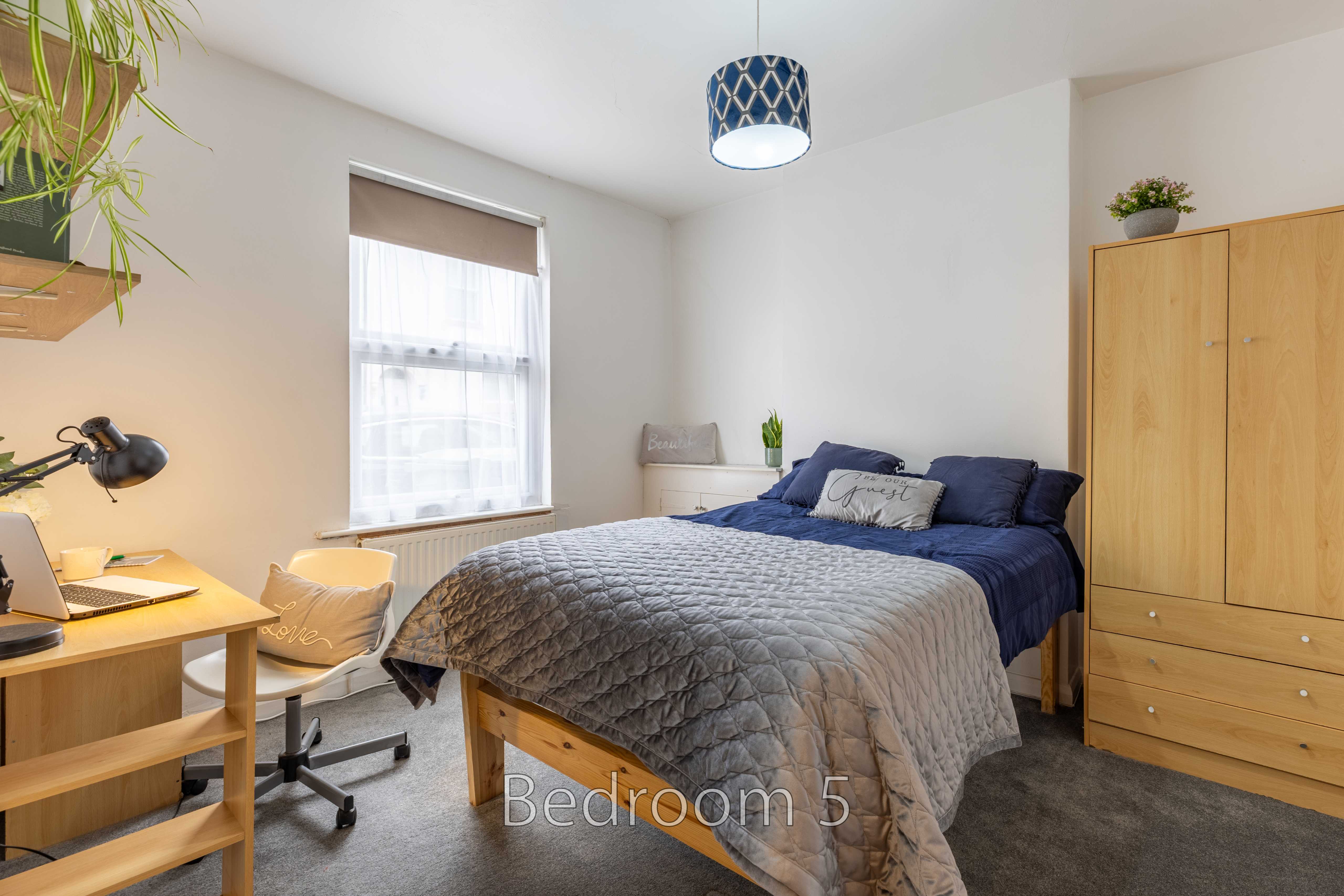 Bedroom with a double bed, desk, chair, wardrobe and window.