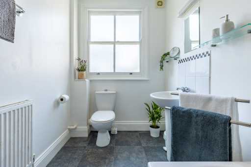 Bright bathroom with a toilet, sink, bathtub, window, radiator and tiled walls.